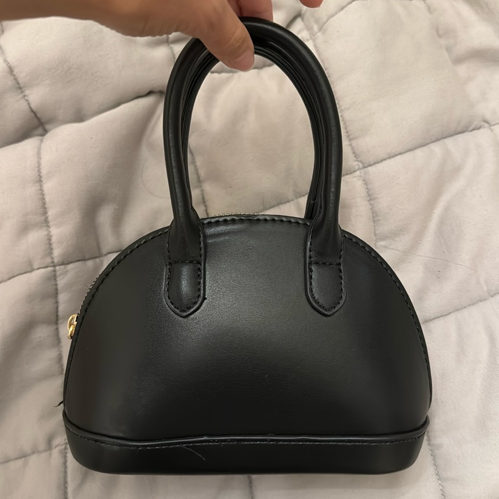 Mini black purse with detachable gold chain strap.